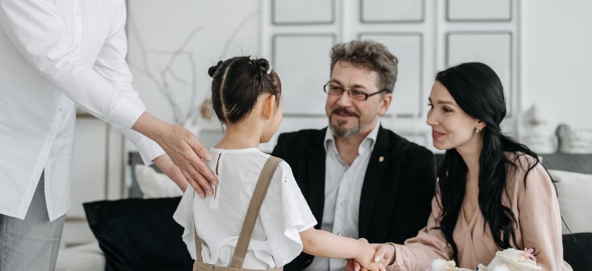 A touching moment between prospective parents and a child at an adoption center indoors.