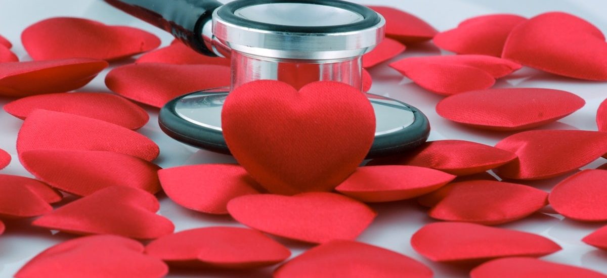 a stethoscope on top of a pile of red hearts
